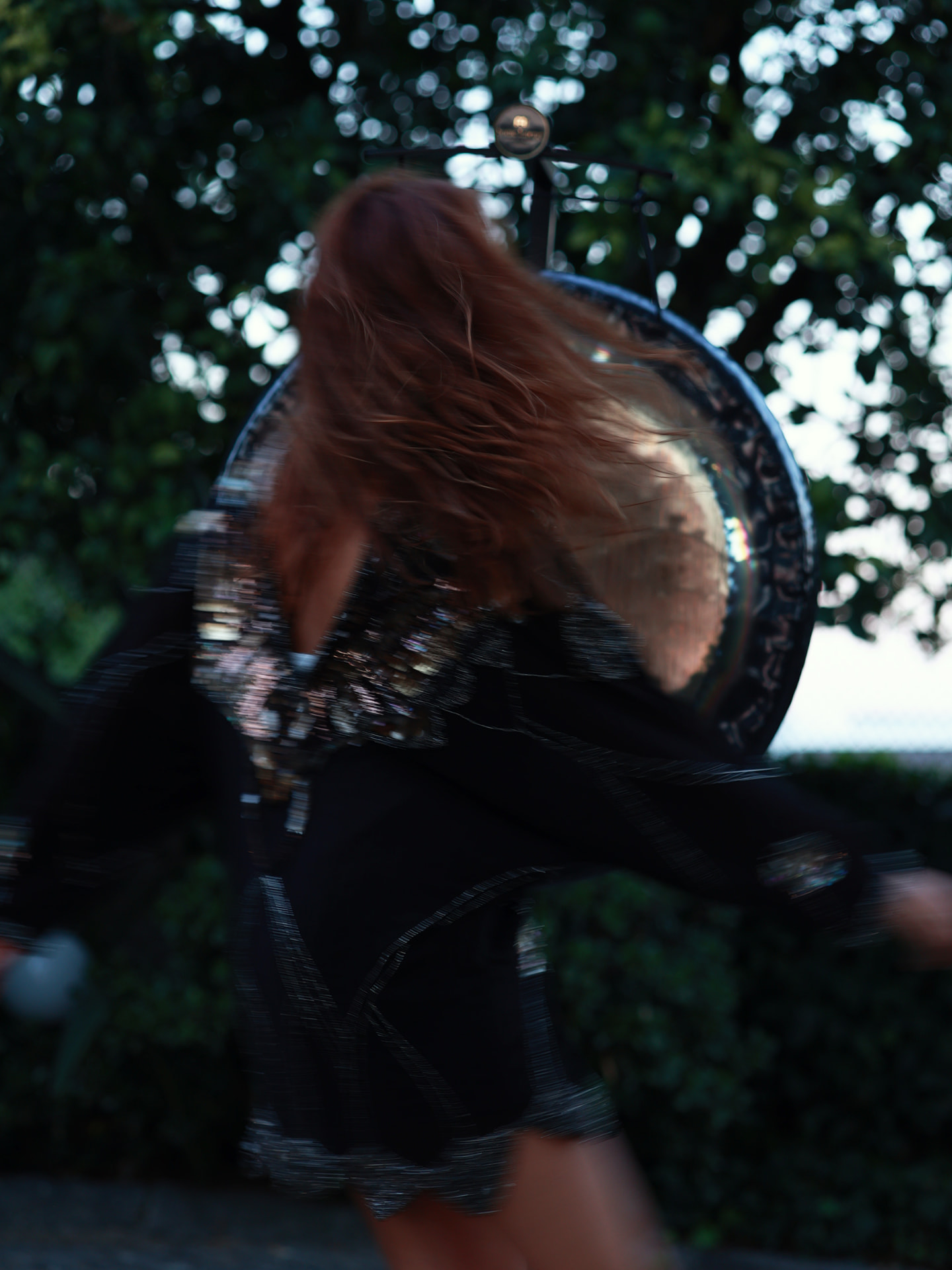 Movement blurred in front of a gong at dusk
